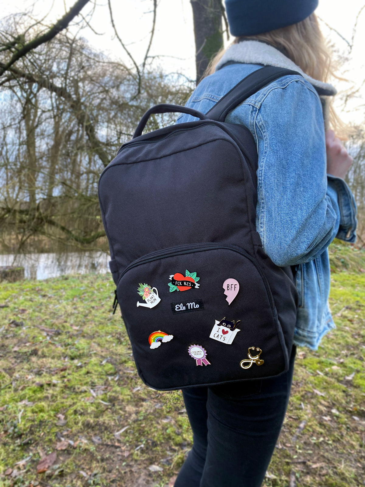 Ela Mo™ Pin für Rucksäcke | Cat. Eine Frau mit dem Rucksack und mehreren kleinen Pins darauf.