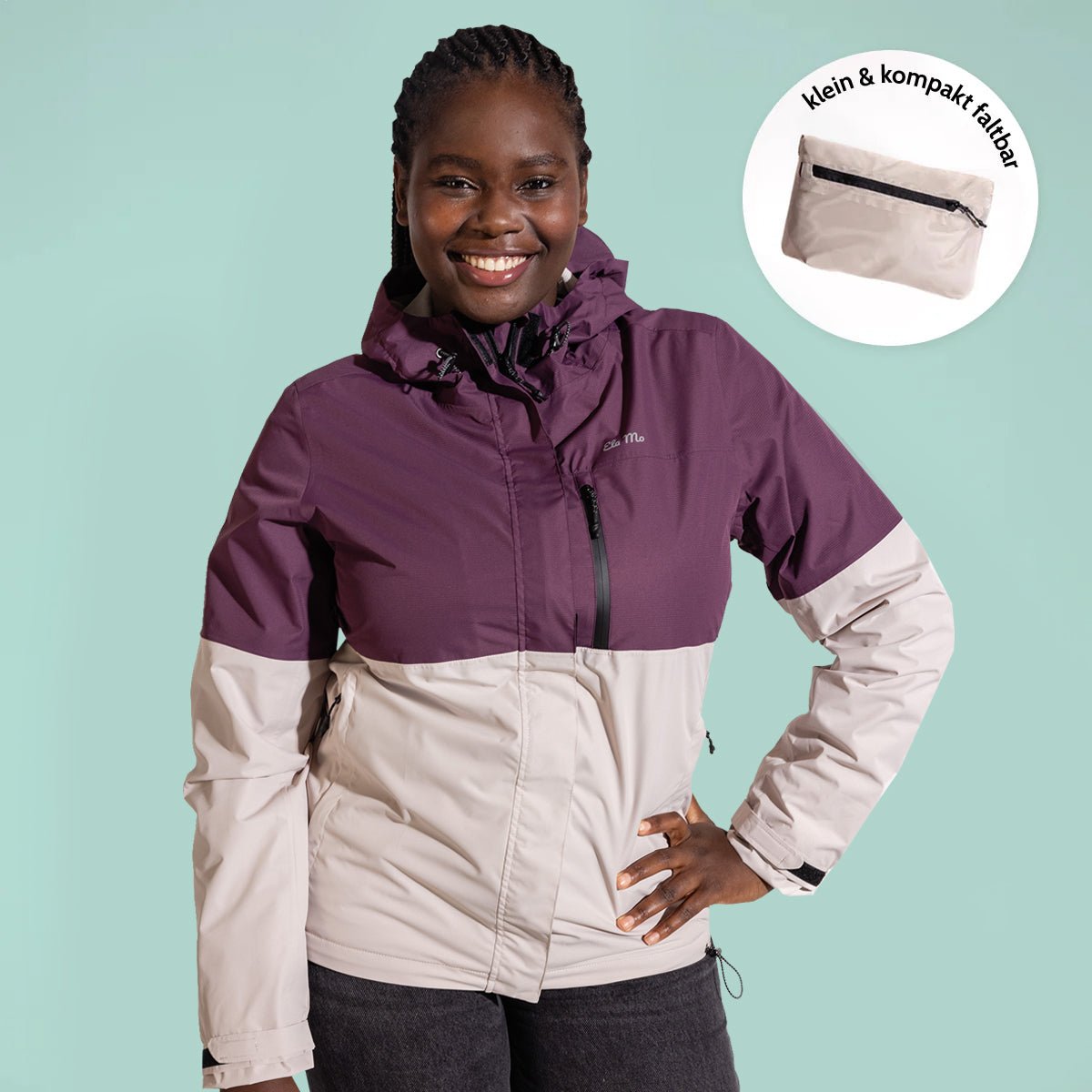 Ela Mo™ Regenjacke | Grape. Eine Frau in einer kompakt faltbaren Regenjacke vor hellgrünem Hintergrund.