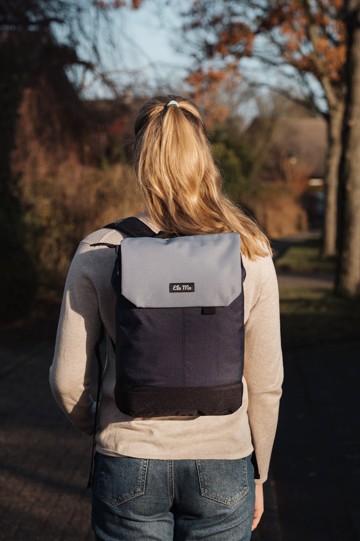 Ela Mo™ Daypack Rucksack | Nightblue. Eine Frau mit dem Rucksack auf dem Rücken im Freien – alltäglicher Lifestyle.