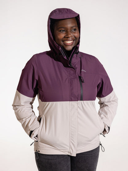 Ela Mo™ Regenjacke | Grape. Eine Frau in bequemer Regenjacke mit Reißverschluss und Kapuze auf dem Kopf.