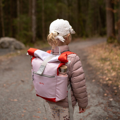 Ela Mo™ Kinderrucksack (6-10 Jahre) | Cotton Candy.Ein Mädchen trägt den rosa Rucksack mit einer Flasche in der Seitentasche