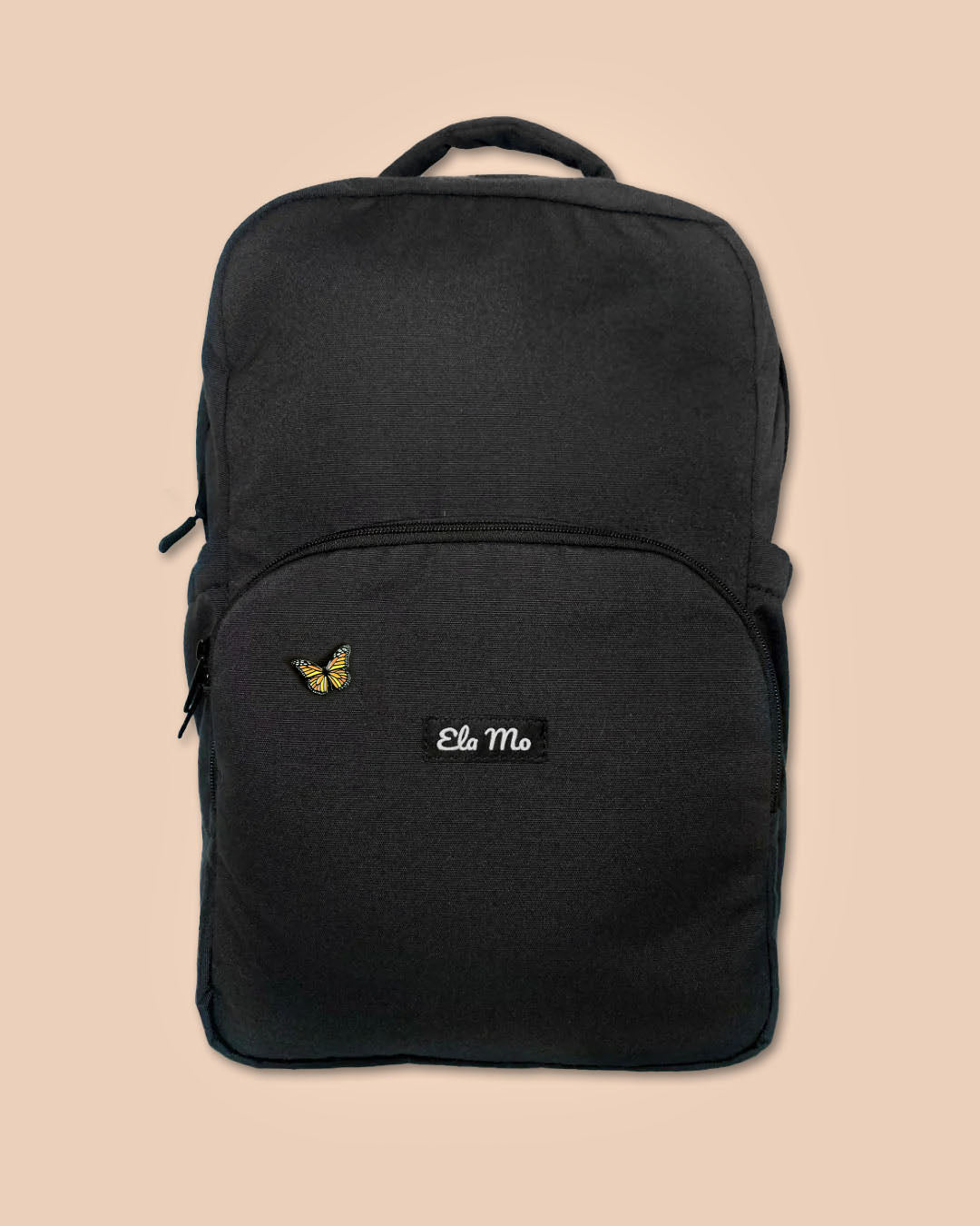 Ela Mo™ Mini Pin für Rucksäcke | Butterfly. Ein kleiner Schmetterlings-Pin am Rucksack, vor gelbem Hintergrund.