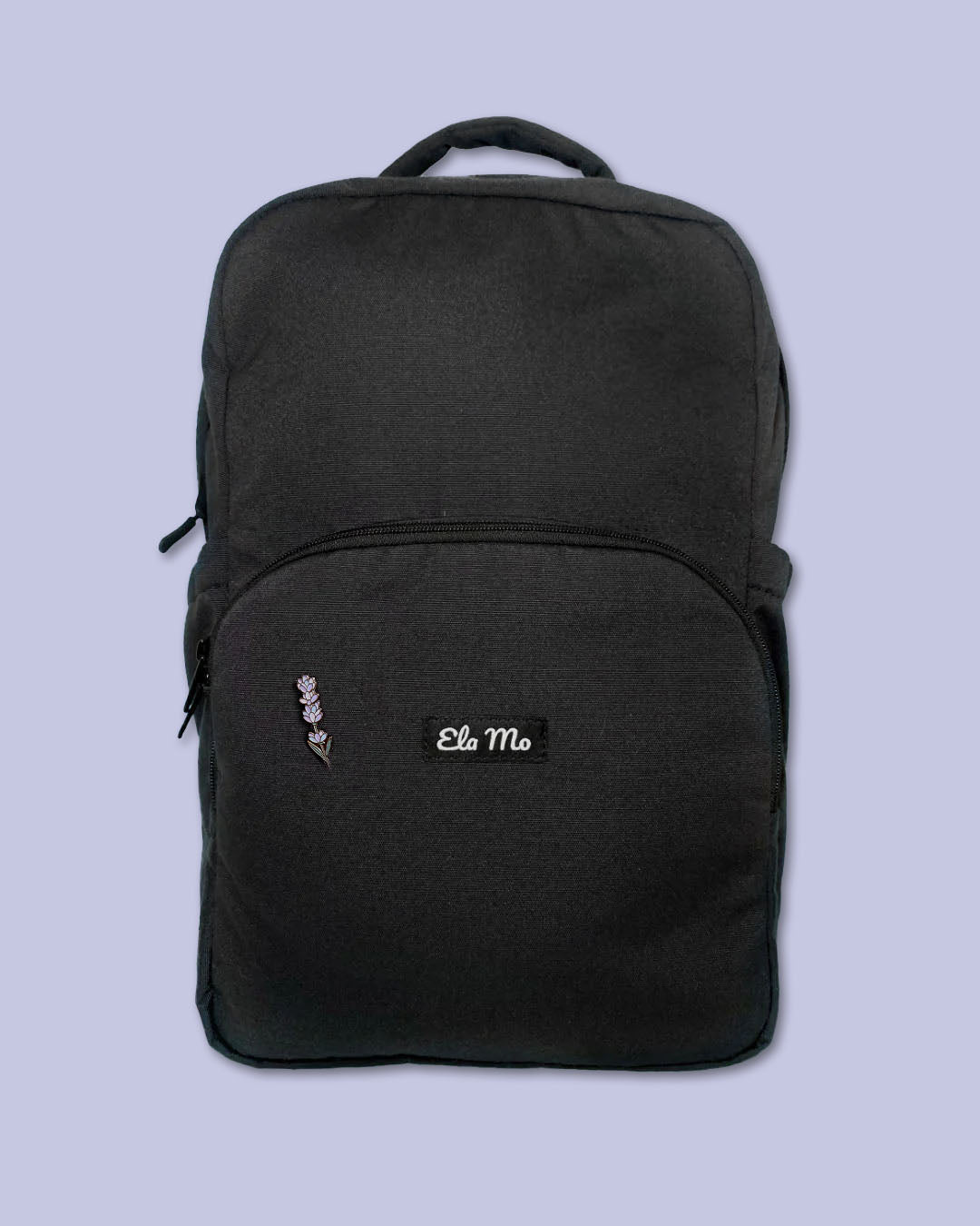 Ela Mo™ Mini Pin für Rucksäcke | Lavender. Ein kleiner Lavendel-Pin am Rucksack, vor lila Hintergrund.