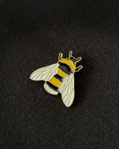 Ela Mo™ Mini Pin für Rucksäcke | Biene. Nahansicht eines kleinen Pins, befestigt auf dem schwarzen Rucksack.