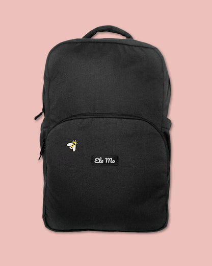 Ela Mo™ Mini Pin für Rucksäcke | Biene. Ein kleiner Pin ist vorne am schwarzen Rucksack befestigt.