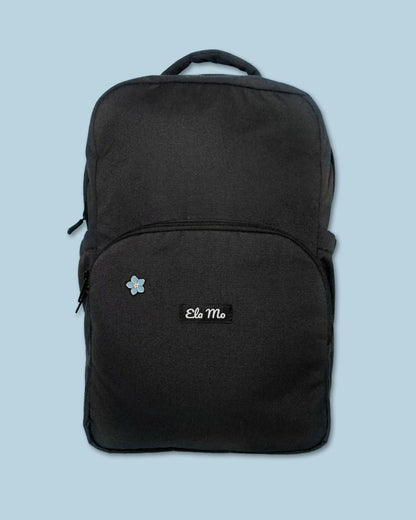 Ela Mo™ Mini Pin für Rucksäcke | Vergissmeinnicht. Ein kleiner Pin ist vorne am schwarzen Rucksack befestigt.