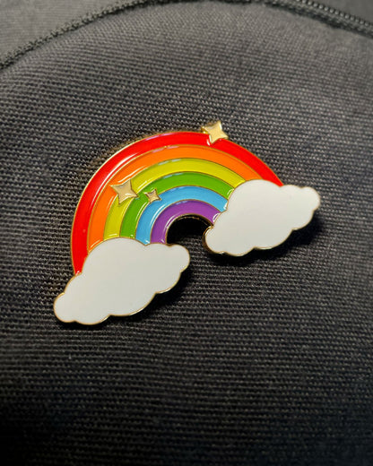 Ela Mo™ Pin für Rucksäcke| Rainbow. Nahansicht eines kleinen Pins, befestigt auf dem schwarzen Rucksack.