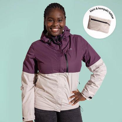 Ela Mo™ Regenjacke | Grape. Eine Frau in einer kompakt faltbaren Regenjacke vor hellgrünem Hintergrund.